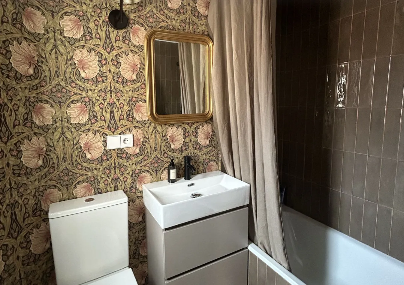 El baño terminado, con papel pintado floral y azulejo verde