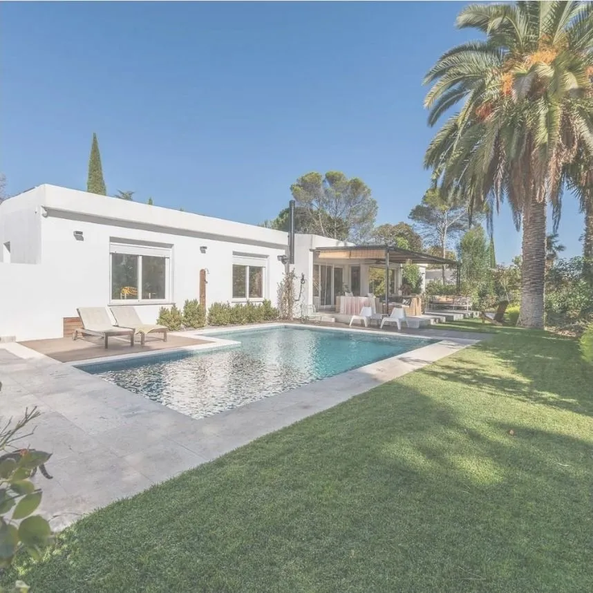 La piscina y el porche de la casa, desde el césped