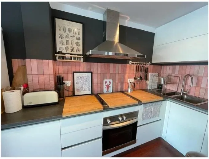 La cocina terminada de Mahón, con azulejo rosa, campana de acero y muebles blancos
