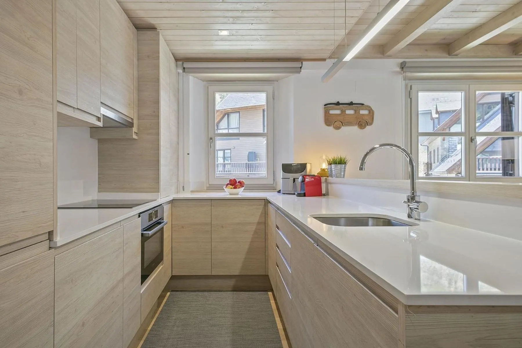 La cocina blanca, con la encimera clara bajo dos ventanas