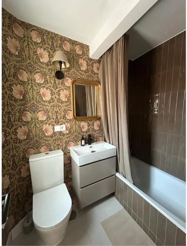 El baño terminado de Riaza 1: papel pintado floral, espejo dorado y azulejo tabaco