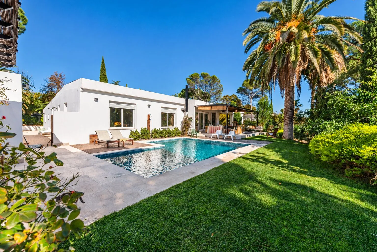 La casa terminada desde el jardín, con la piscina y la palmera