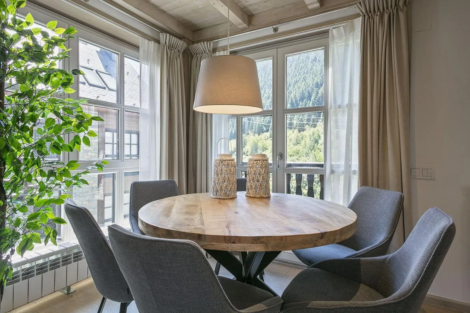 El comedor junto a la ventana: mesa redonda de madera y sillas grises