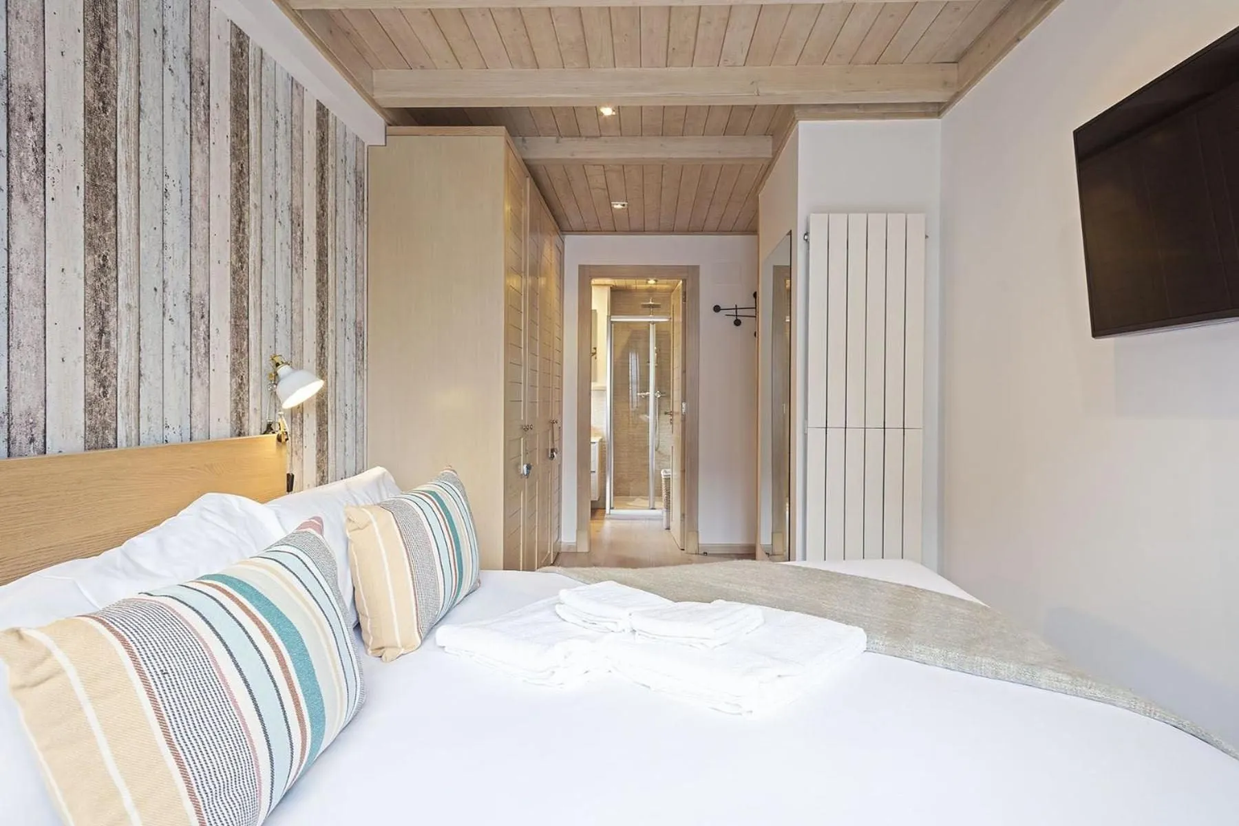 Un dormitorio de matrimonio con ropa de cama de rayas y paredes de madera