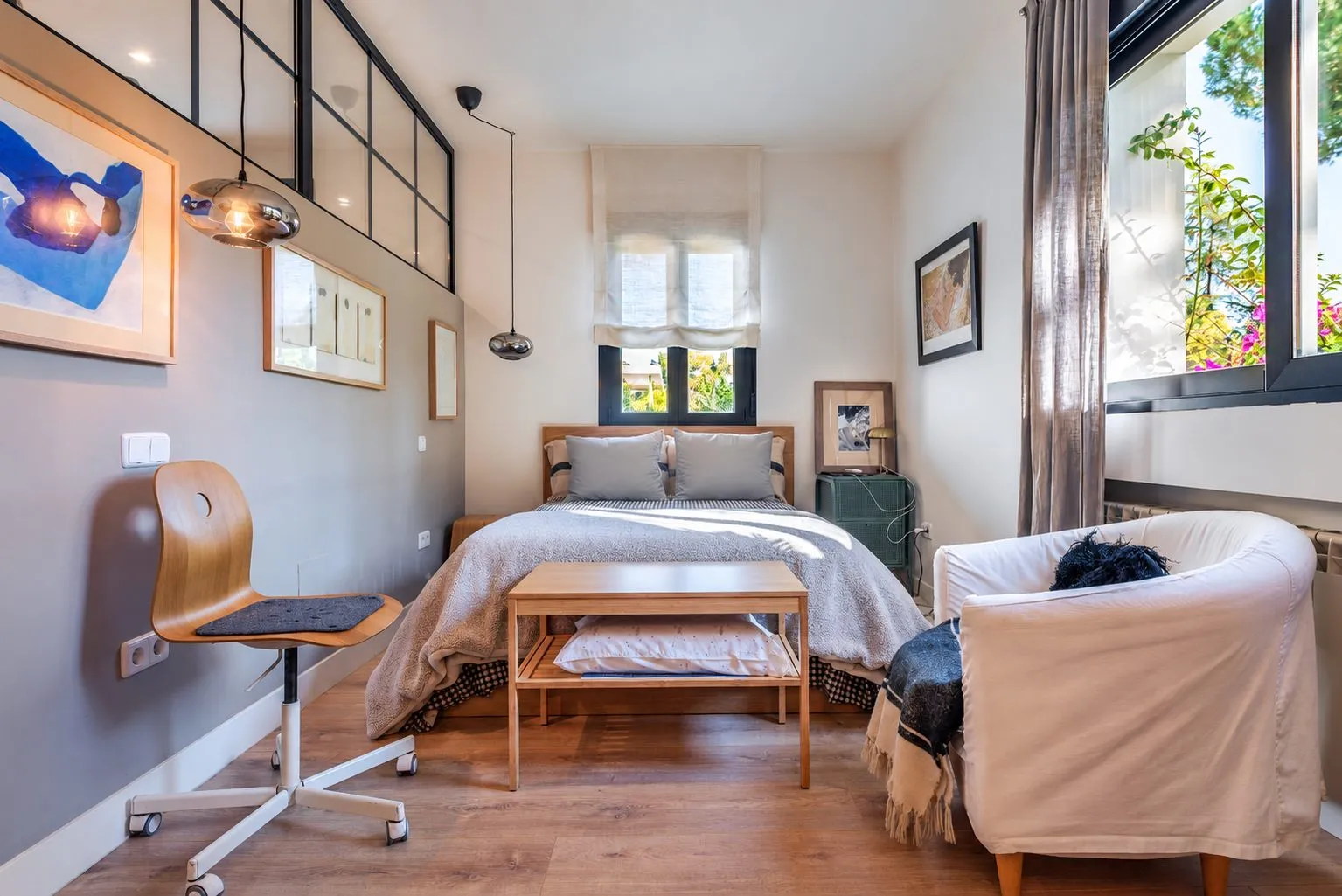 Un dormitorio con escritorio, ventana de cuarterones y una butaca blanca