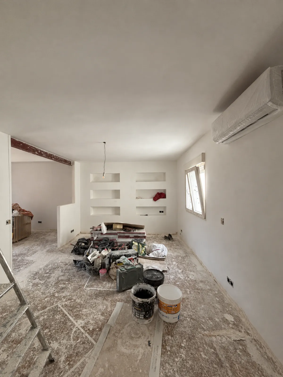 La misma habitación en obra: enlucida de blanco, con las hornacinas ya abiertas en el tabique
